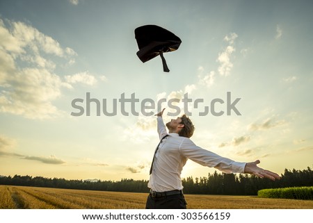 Happy Successful Young Businessman Throwing His Coat in the Air for being Free of Something with Wide Open Arms at the Field During Sunset.