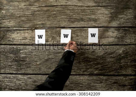 High angle view of web developer placing three white papers spelling WWW on a textured rustic wooden planks. Conceptual of internet web professionals.