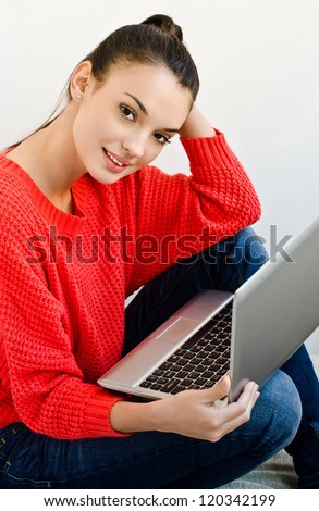Attractive brunette student girl working on the laptop from home, relaxed and smiling.