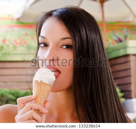 Beautiful woman eating a delicious ice cream. Girl sitting at a terrace on a hot day eating a delicious vanilla chocolate ice cream.