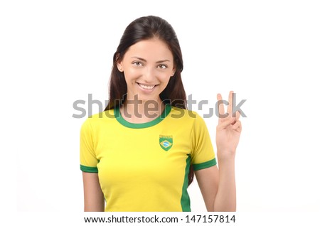 Girl signing victory for Brazil. Attractive fan with Brazilian flag on her yellow t-shirt. Isolated on white.