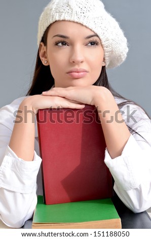 Beautiful student girl with books. Beautiful brunette student girl thinking. Dressed in white wearing a beret.