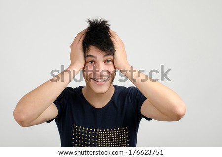 Young man with crazy hair holding his head smiling. Man being happy surprised and amazed. Man with different facial expressions.