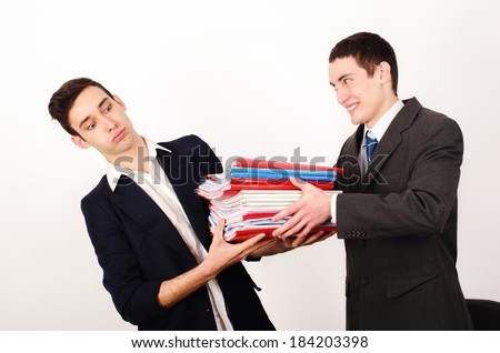 Desperate worker receiving a lot of paper work from his happy boss. Unhappy business man with a big pile of files to work on.