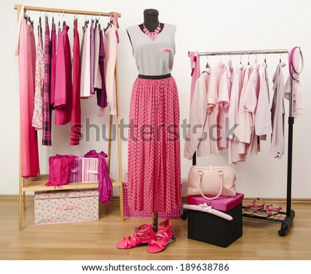 Dressing closet with pink clothes arranged on hangers and an outfit on a mannequin. Wardrobe full of all shades of pink clothes, shoes and accessories.