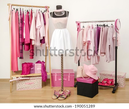 Dressing closet with pink clothes arranged on hangers and an outfit on a mannequin.  Wardrobe full of all shades of pink clothes, shoes and accessories.