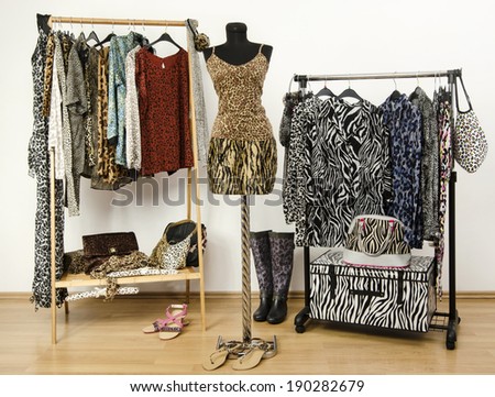 Dressing closet with animal print clothes arranged on hangers. Cheetah print top and tiger print skirt on a mannequin. Colorful wardrobe with jungle pattern clothes and accessories.