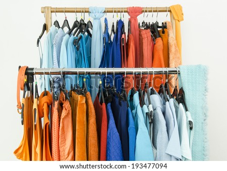 Close up on complementary colors clothes on hangers in a store. Shades of orange and blue clothes and accessories hanging on a rack nicely arranged.