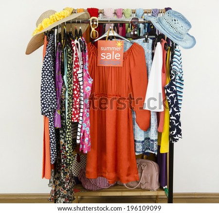 Cute summer outfits displayed on hangers with a big sale sign. Clearance rack with colorful summer clothes and accessories.