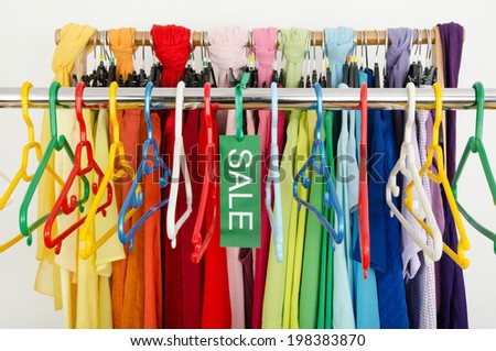Empty rack of clothes and hangers after a big sale. Sale sign for summer clothes on a clearance rack with colorful summer outfits and accessories.