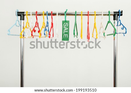 Rack of clothes with empty hangers and a sale sign. Empty colorful plastic hangers after a big sale.