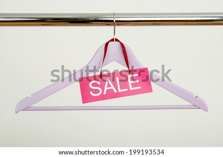 Empty hanger on a rack of clothes with the sale sign. Close up on purple wood hanger, clearance concept.