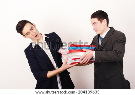 Desperate worker receiving a lot of paper work from his happy boss. Unhappy business man with a big pile of files to work on.