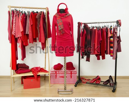 Wardrobe with red clothes arranged on hangers and an outfit on a mannequin. Dressing closet full of all shades of red clothes, shoes and accessories.