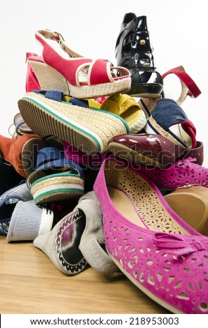 Close up on big pile of colorful woman shoes. Untidy stack of shoes thrown on the ground.
