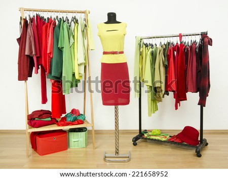 Dressing closet with complementary colors red and green clothes arranged on hangers and an outfit on a mannequin. Wardrobe full of all shades of green and red clothes and accessories.
