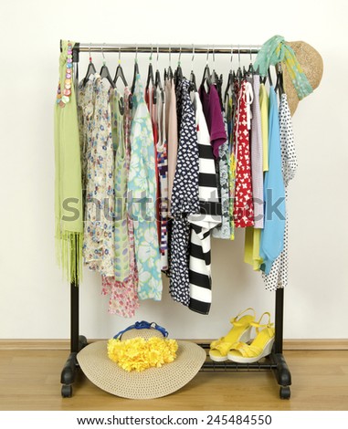 Wardrobe with summer clothes nicely arranged. Dressing closet with colorful clothes on hangers,sandals, hats and accessories.