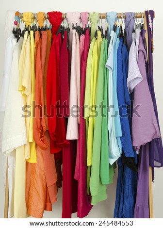 Close up on color coordinated clothes on hangers in a store. All colors clothes hanging on a rack nicely arranged.