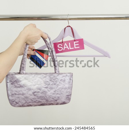 Unrecogniazable woman hand shopping with credit cards on sale. Empty hanger on a rack of clothes with the sale sign.