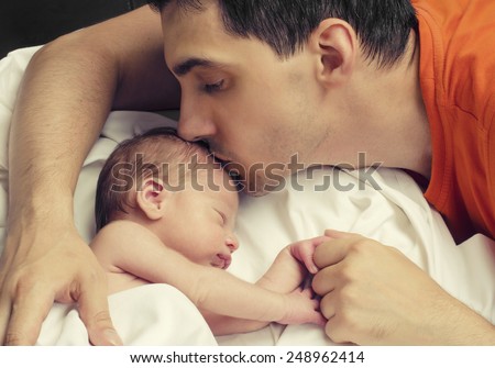 Loving father kissing his new born baby.Father kissing his baby boy forehead while his sleeping and holding hands. Parent love.