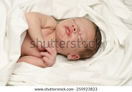 New born baby boy smiling in his sleep. Small baby happy making cute faces during his nap.