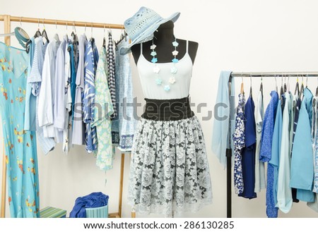 Dressing closet with blue clothes arranged on hangers and an outfit on a mannequin. Wardrobe full of all shades of blue clothes, shoes and accessories.