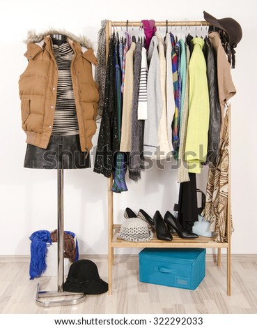 Wardrobe with clothes arranged on hangers and a winter outfit on a mannequin. Dressing closet with autumn clothes and accessories. Tailor\'s dummy wearing a winter vest with leather skirt.