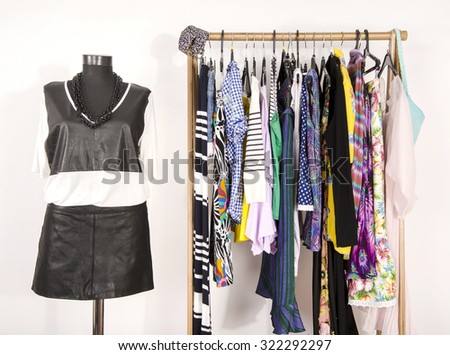 Dressing closet with colorful clothes arranged on hangers and an outfit on a mannequin. Wardrobe with clothes and accessories. Tailor\'s dummy wearing a black leather blouse and skirt.
