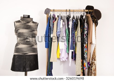 Dressing closet with colorful clothes arranged on hangers and an outfit on a mannequin. Wardrobe with clothes and accessories. Tailor\'s dummy wearing a striped turtleneck and a black leather skirt.