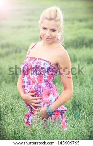 beautiful blonde in a summer dress posing in a oat field, in a nature ...
