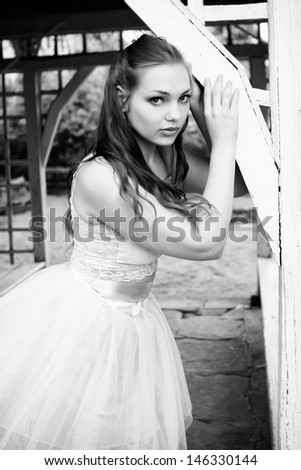 Beautiful brunette in white undershirt and white scarf and heel shoes posing at the gazebo in exterior, fashion photography, black and white photo