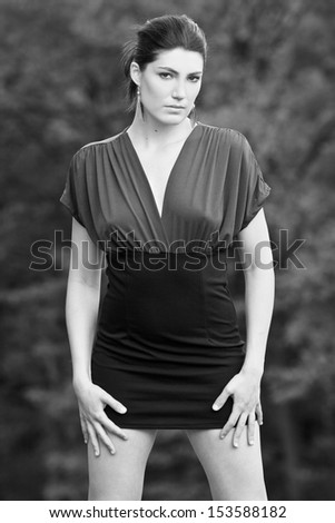Beautiful brunette in a dress posing on a golf course, in a nature,  fashion photography, black and white photo