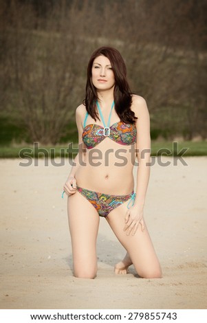 Beautiful brunette is posing on a golf course. She is wearing a bikini. Fashion photography.