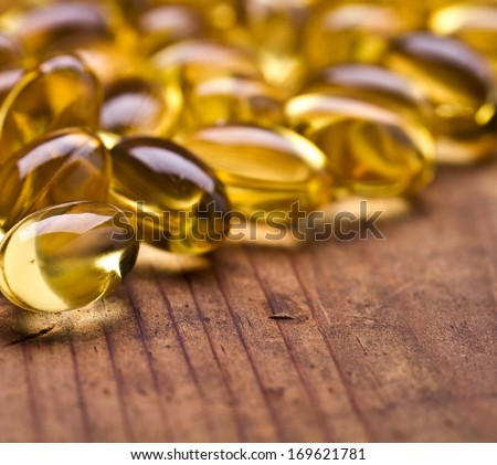 Cod liver oil omega 3 gel capsules isolated on wooden background. Vitamin capsuls