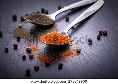 red and black pepper powder on silver spoons