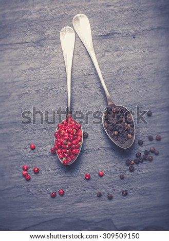 Red  and black peppercorns on silver spoons