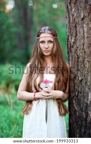 Young pagan Slavic girl with a dagger in the forest