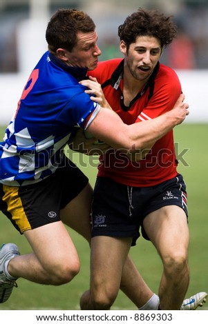 Man in red jersey being grabbed by opponent in blue jersey at Rugby 7s 2007 tournament