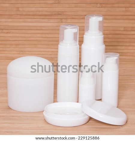 Open jar of cream and other body care cosmetics on wooden background