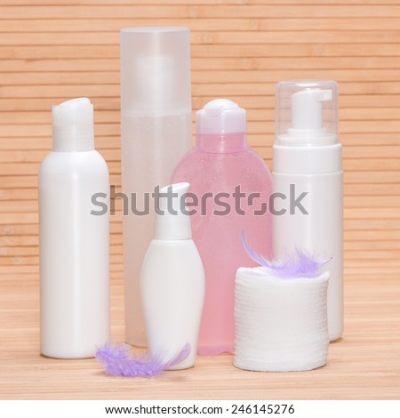 Soft beauty products for sensitive skin concept: different facial cosmetics with cotton pads and feathers on wooden surface
