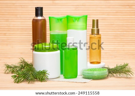Natural hair care cosmetics and accessories: sea salt, shampoo, conditioner, balm, mask, oil, wooden combs with pine branches on wooden surface