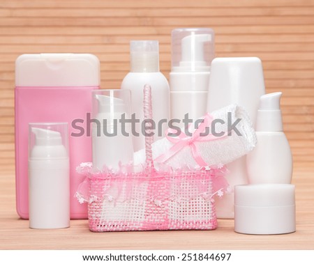 Collection of cosmetic products for skincare with a charming wicker basket and towel on a bamboo mat. White and pink colors
