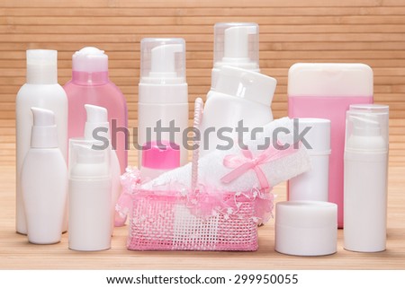Different cosmetic products for skincare on wooden surface. Various facial cleansers, makeup removers, day and night creams, antiperspirant deodorant with cute wicker basket and towel