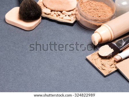 Makeup products and accessories to even out skin tone and complexion: correctors, liquid foundation, loose and compact powder, concealer pencil, makeup brushes and cosmetic sponge. Copy space
