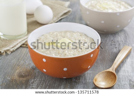 Oatmeal porridge with butter, milk and eggs on a wooden table