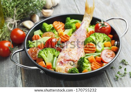 Fried fish with vegetables in the  pan