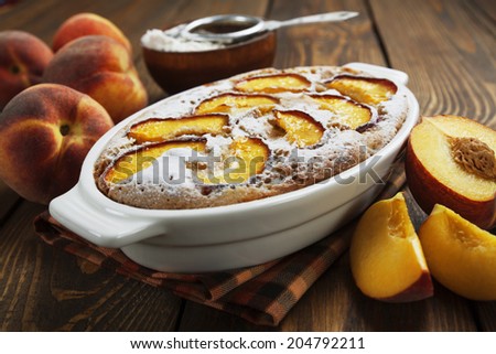 Peach pie in a ceramic pot on the wooden table