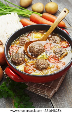 Cabbage soup with meatballs and tomatoes in a bowl