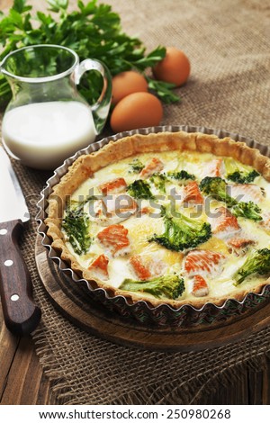 Quiche with broccoli and fish on a wooden table