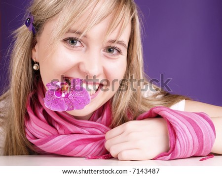 Beautiful young woman with orchid in mouth.